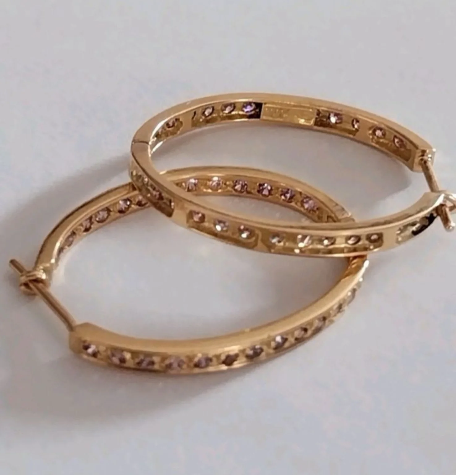 Paire de boucles d’oreilles dorées ornées de petites pierres, gros plan.