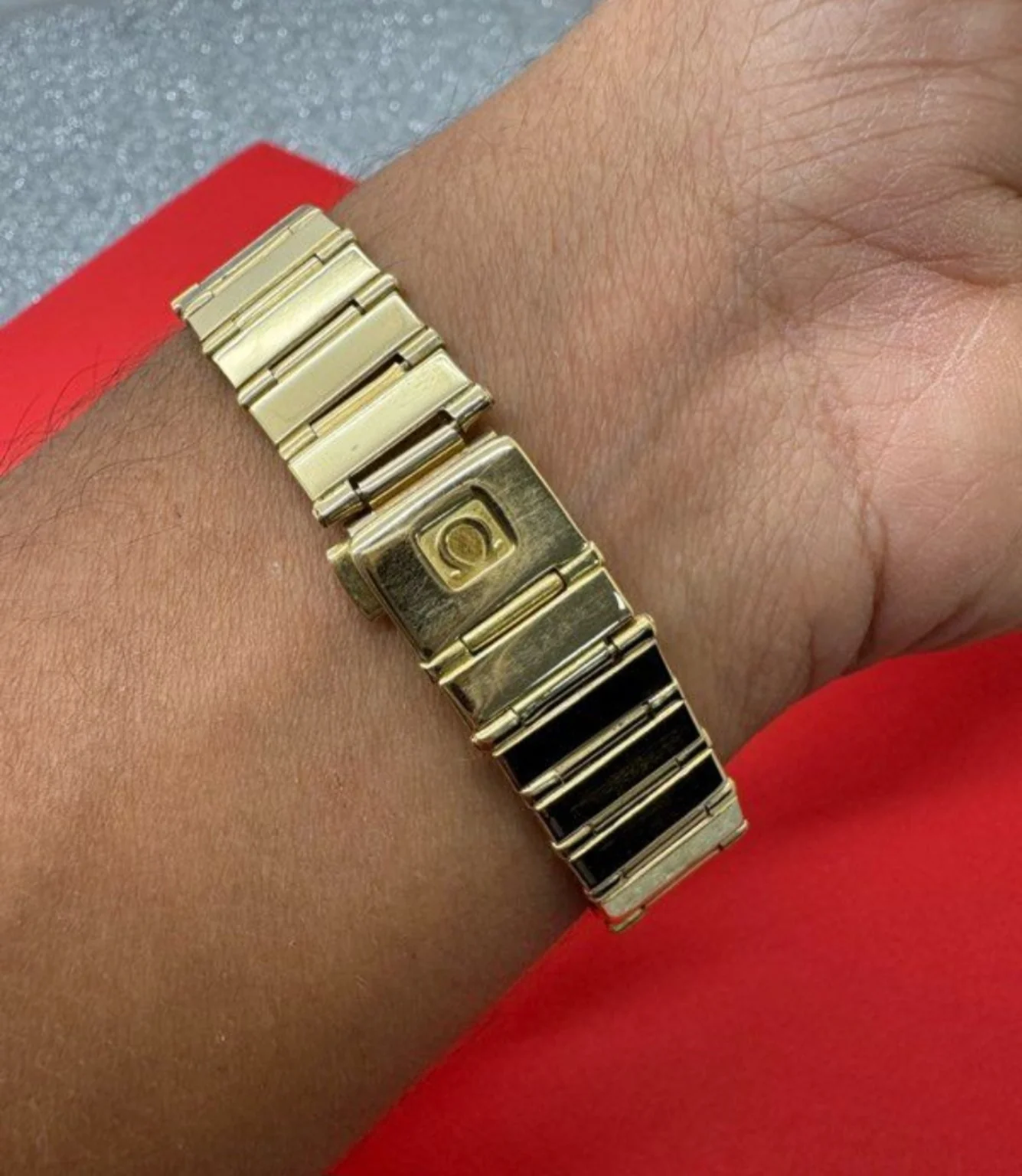Gros plan du bracelet doré et du fermoir d’une montre portée au poignet.