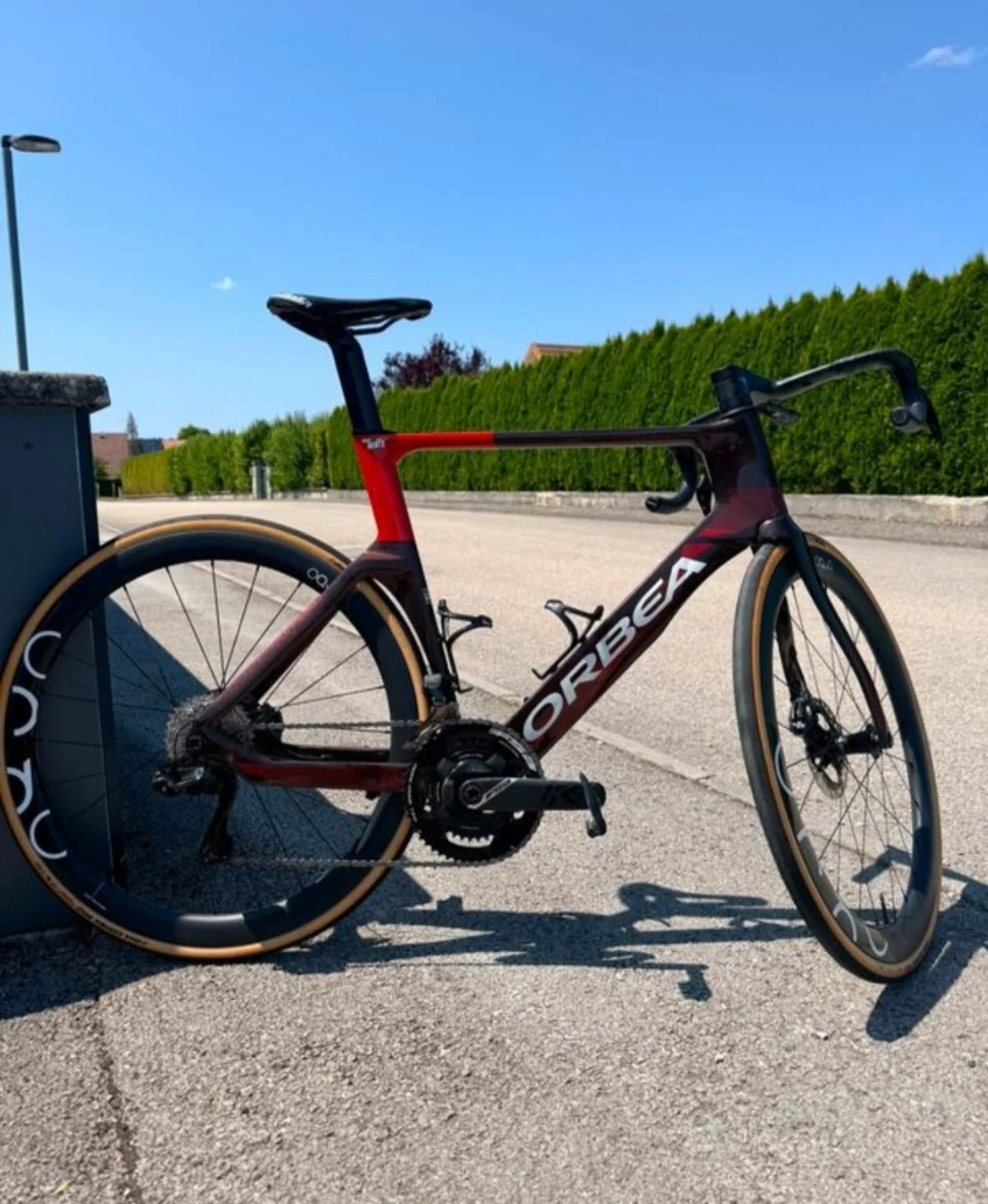 Vélo de route Orbea rouge et noir photographié en extérieur.